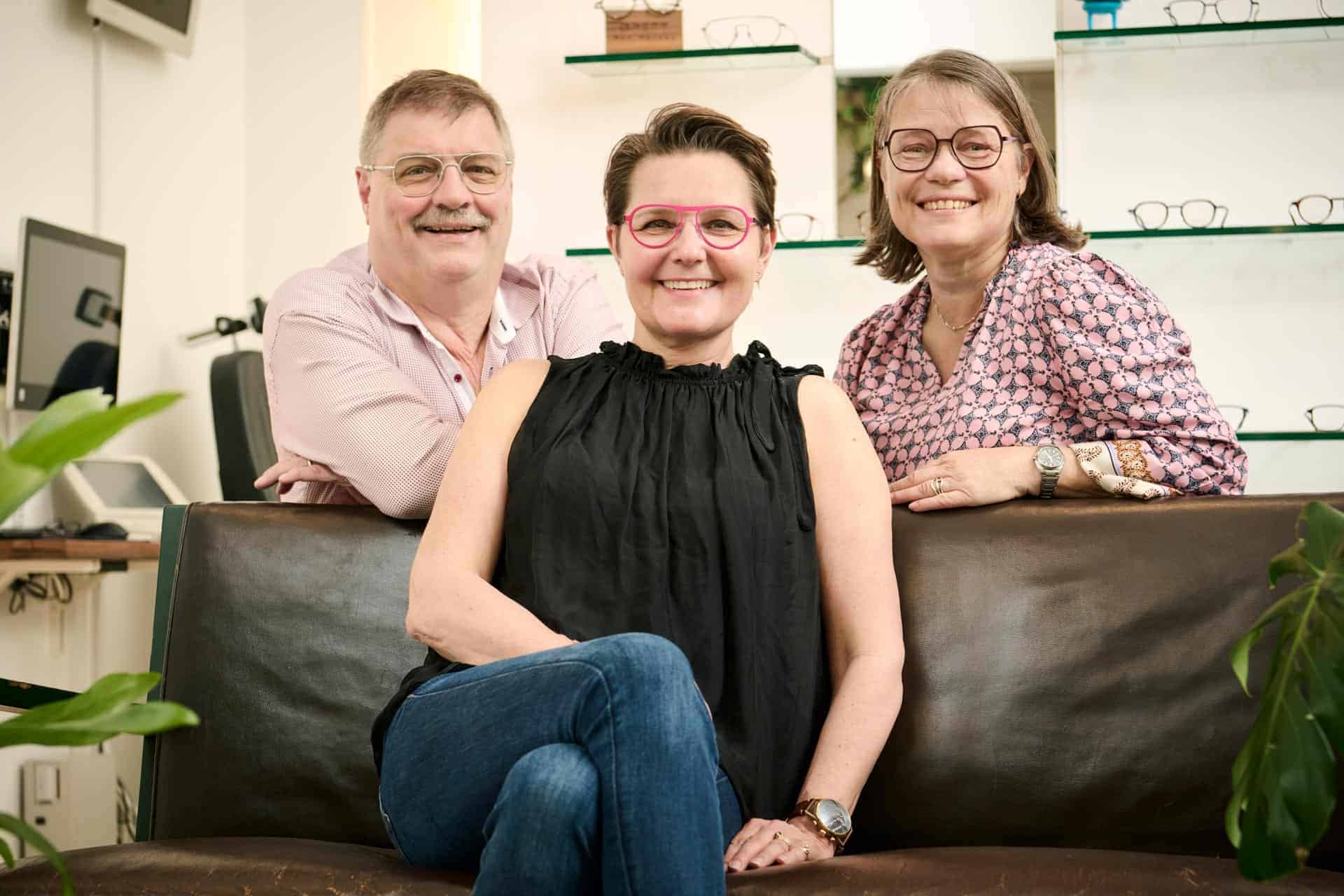 Fire smilende, professionelle optikere hos No. 1 Optik på en lædersofa