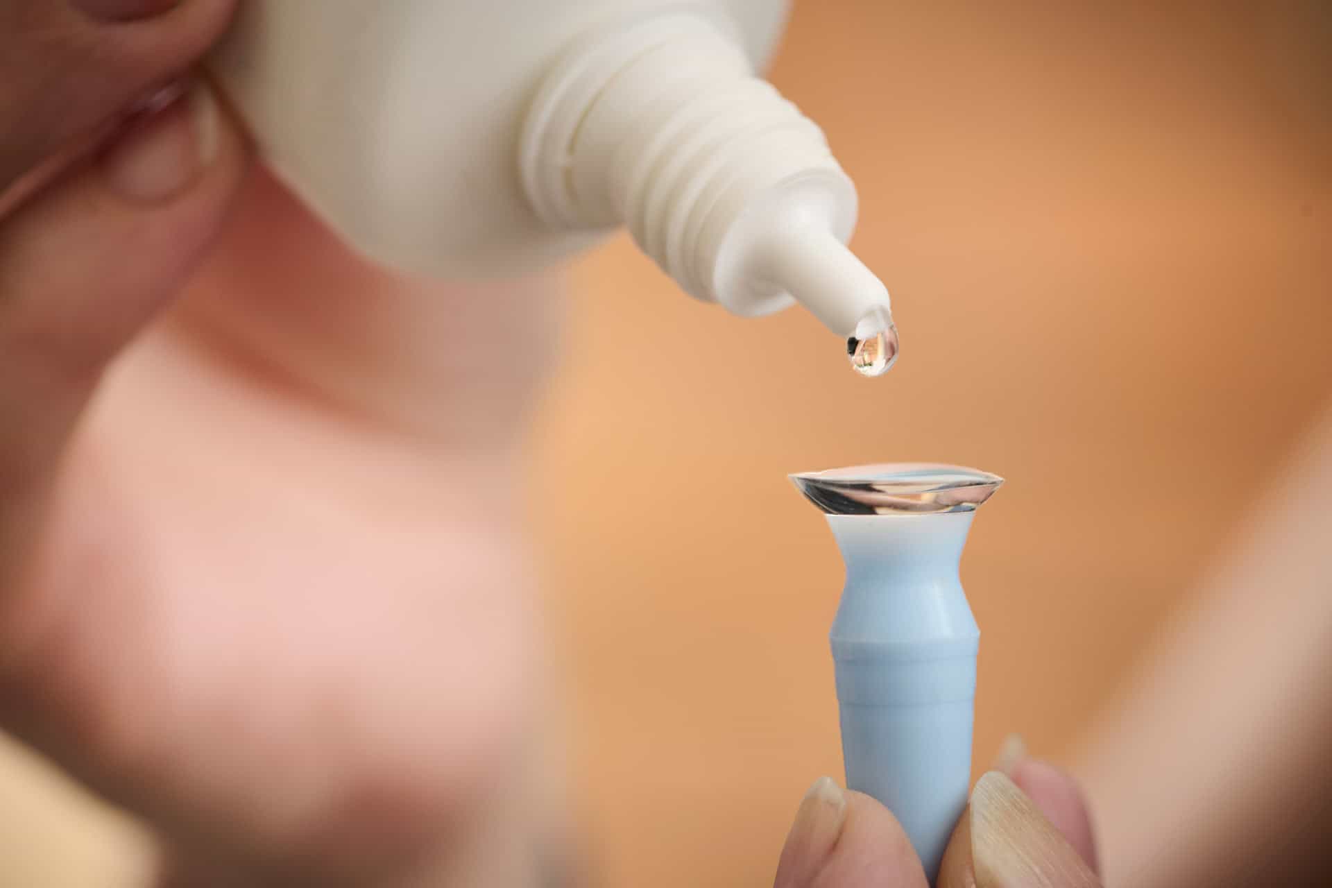 Linsevæske dryppes på en kontaktlinse placeret på et påsætningsværktøj hos No. 1 Optik